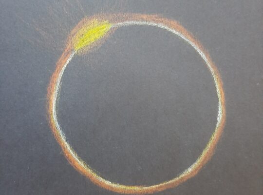 Black circle with a yellow and orange glow around it and one brighter yellow spot in the top